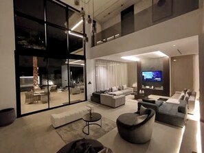 A modern living room with a large TV, sofas, a coffee table, and a glass door leading to an outdoor area. - Modern villa at the new Amelkis Golf Resort Marrakech (Marrakech)