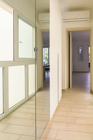 Ein Flur mit Glastür, im Hintergrund ein Essbereich und ein Holzboden.