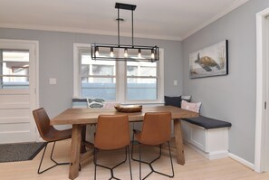 A dining area with a wooden table, four chairs, a bench, and a pendant light. - NEW Prime Rehoboth Beach Downtown  5BR Coastal Cottage Walk to Beach & Boardwalk (Rehoboth Beach)