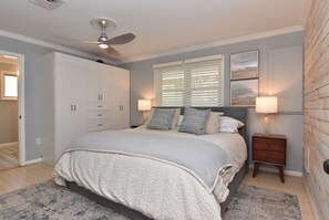 A bedroom with a bed, ceiling fan, nightstands, and a window with blinds. - NEW Prime Rehoboth Beach Downtown  5BR Coastal Cottage Walk to Beach & Boardwalk (Rehoboth Beach)