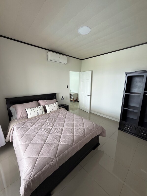 Une chambre à coucher comprenant un lit, une armoire, une porte et un appareil de climatisation.