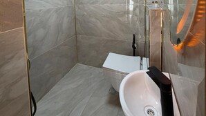 Un baño moderno con cabina de ducha de vidrio, un lavabo blanco y un espejo grande.