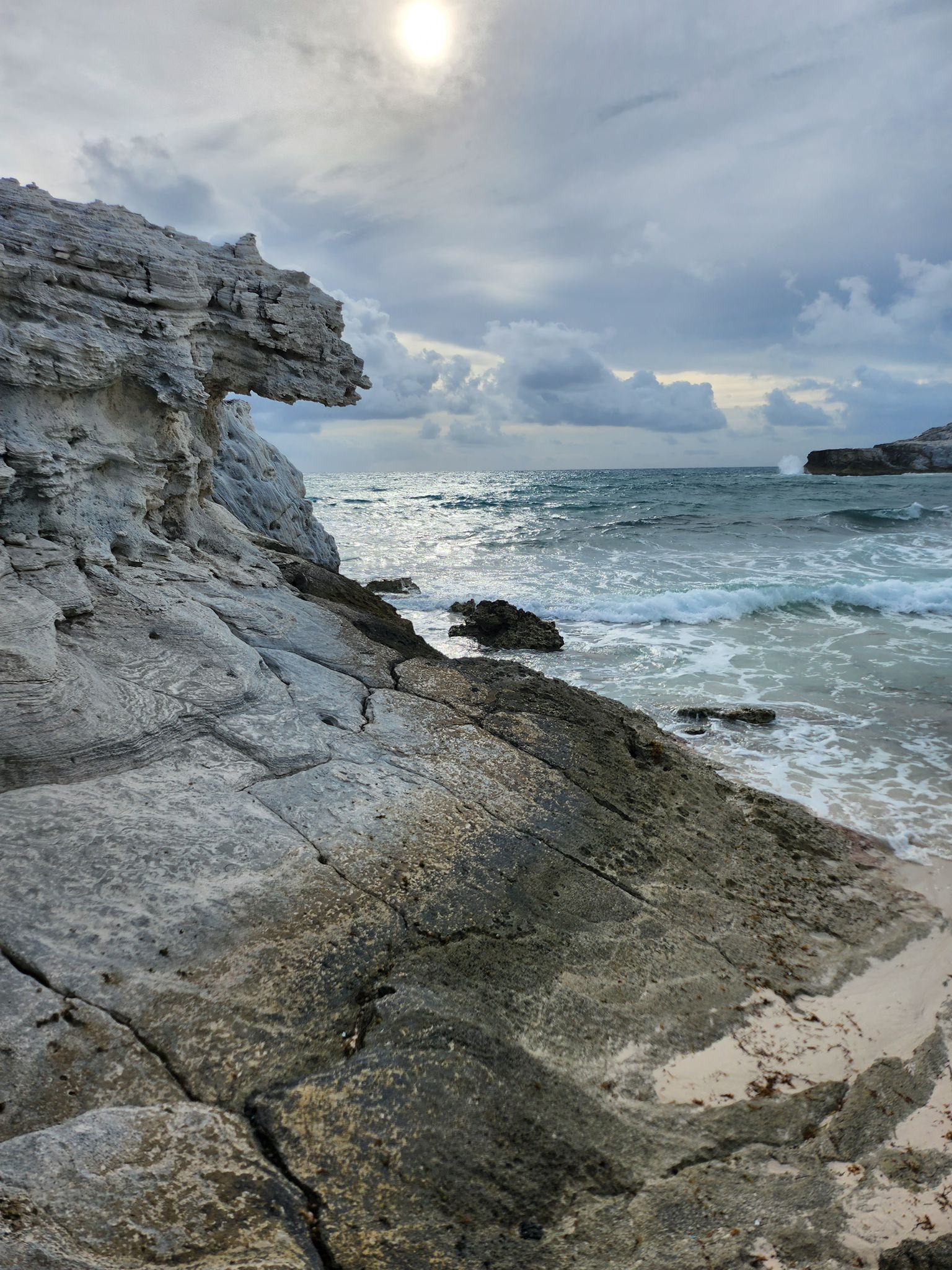 Une côte rocheuse avec une grande formation rocheuse et des vagues qui s’écrasent sur le rivage.