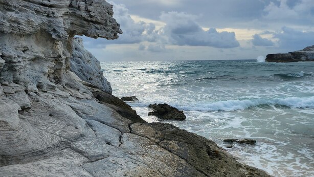 A rocky coastline with a large rock formation and waves crashing against the shore. - Anchorage - 4BR Luxury Beach House in Exuma – 50ft to calm water, Sleeps 10 (Black Point)