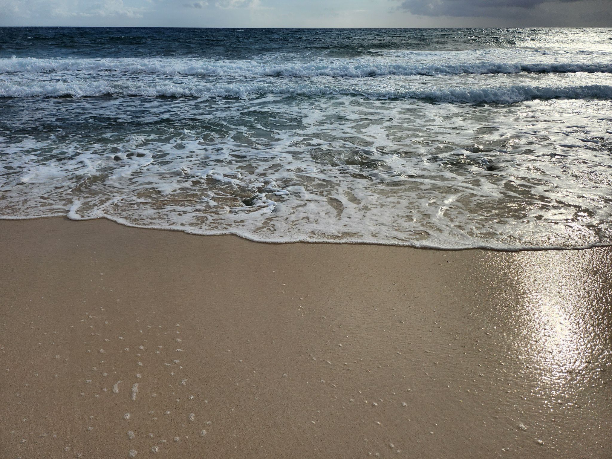 A beach with waves approaching the shore.
