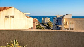 A coastal residential area with modern buildings, a clear view of the sea, and a paved walkway. - Concy's Jacuzzi - Private Suite with Sea View and Exclusive Terrace (Kaukana)