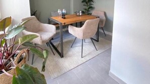 Un coin repas comprenant une table en bois, quatre chaises, un luminaire suspendu et une plante en pot.