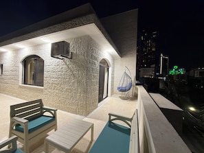 A building with a textured facade, outdoor seating, and a hanging chair. - 302 JRE Rooftop With Stunning Boulevard Veiw (Amman)