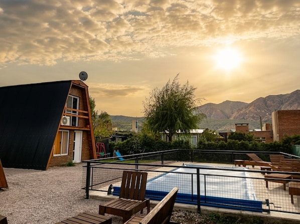 A modern building with a sloped roof, a pool, and outdoor seating.
