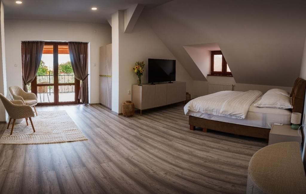 A bedroom with a large bed, a TV, and a balcony with curtains.
