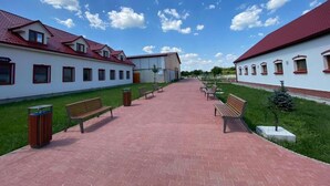 Un chemin menant à un bâtiment doté de nombreuses fenêtres et d’un toit rouge.