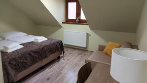 Une chambre à coucher avec un lit, un bureau, une chaise, une fenêtre et un radiateur.