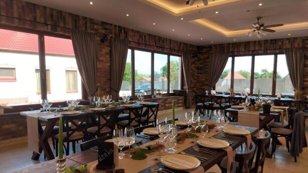 Un restaurant doté de nombreuses tables préparées pour le service, de grandes fenêtres et de ventilateurs de plafond.