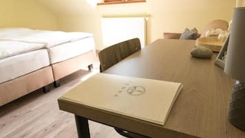 A room with a bed, a dining table, and a window.