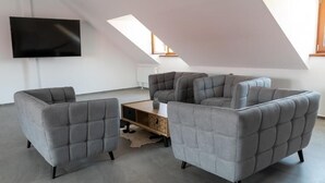 Un salon moderne avec un canapé d’angle, un téléviseur à écran plat et une lucarne.
