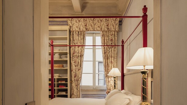 Ein Schlafzimmer mit einem Bett, Nachttischlampen, einem Nachttisch aus Holz, einem Kleiderschrank und einem Fenster mit Vorhängen.