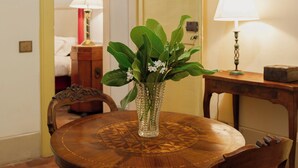 Ein Essbereich mit einem runden Holztisch, rot gepolsterten Stühlen, einer Blumenvase und einer Lampe auf einem Beistelltisch.
