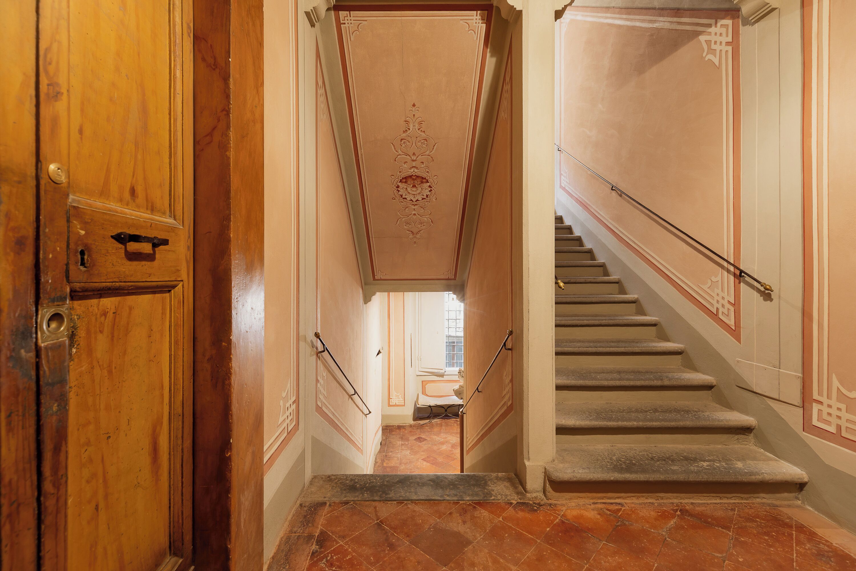 Eine Treppe mit Geländer und einer Holztür links.