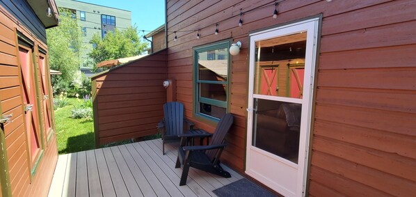 Eine Holzterrasse mit zwei Stühlen und einer Tür zu einem Bereich mit Moskitonetz.