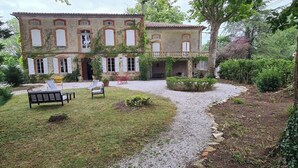 Edifici amb zona de jardí, mobiliari exterior i un camí de grava.