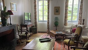Un saló amb un sofà, una taula de centre, una llar de foc, un televisor i una finestra amb cortines.