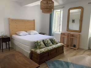 A bedroom with a wooden bed, a bedside table, a nightstand, a mirror, and a window with curtains. - Maison de Maître in green surroundings with secure swimming pool (Saint-Félix-Lauragais)