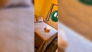 A room with a bed, a window with a curtain, and a green circular object on the wall. - CABANA TEMÁTICA DO HOBBIT - GRAMADO RURAL (Gramado)