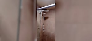Eine Dusche mit Duschkopf und Wandarmatur.