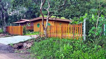 A single-story building with a brown roof and a fenced yard.