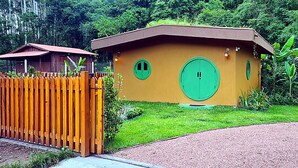 A small, single-story building with a flat roof, a green door, and a small window. - CABANA TEMÁTICA DO HOBBIT - GRAMADO RURAL (Gramado)