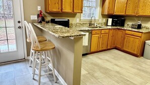 A kitchen with wooden cabinets, a granite countertop, and a bar stool. - Rockland Creek Retreat at LKA with Water Access (Bumpass)