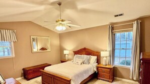 A bedroom with a wooden bed, nightstands, a ceiling fan, a window with curtains, and a mirror on the wall. - Rockland Creek Retreat at LKA with Water Access (Bumpass)