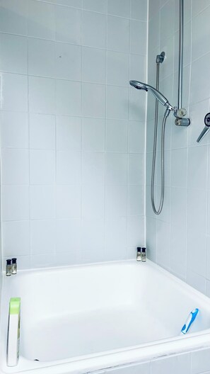 Ein Badezimmer mit einer weißen Badewanne, einer Duschbrause und zwei Seifenspendern.
