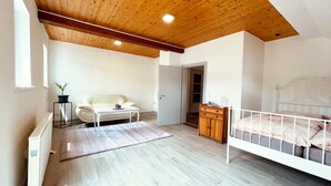 A bedroom with a bed, a white sofa, a small table, a wooden cabinet, and a radiator. - Am Rabenack (Rheinsteig) (Sankt Goarshausen)