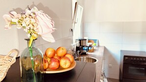 A kitchen counter with a vase of flowers, a plate of apples, a coffee maker, and a toaster. - Am Rabenack (Rheinsteig) (Sankt Goarshausen)