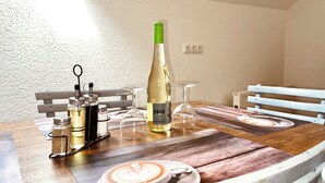 A dining table with a bottle of wine, glasses, condiments, and a placemat with a coffee cup design. - Am Rabenack (Rheinsteig) (Sankt Goarshausen)