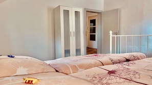 A bedroom with a bed, a wardrobe, and a door leading to another room.