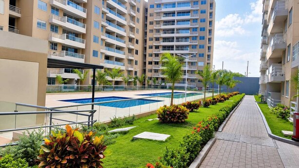 Un edificio residenziale con piscina, un giardino curato e un vialetto lastricato.