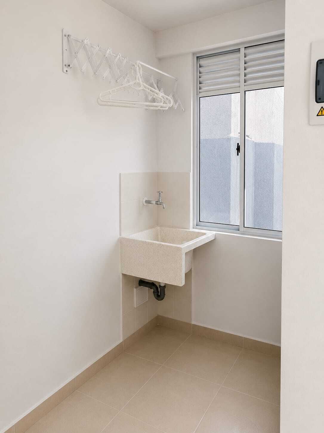 A small bathroom with a sink, a window, and a clothes drying rack.