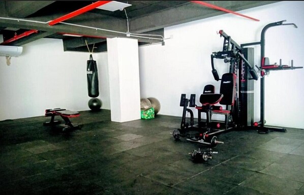 A gym with exercise equipment, a punching bag, and a weight bench.