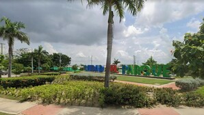 Un'area verde curata con un cartello che riporta la scritta 'CUIDADO EL PARQUE' e un cielo sereno.