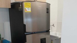 Un frigorifero in acciaio inossidabile in una cucina con un armadio in legno e un lavandino bianco.
