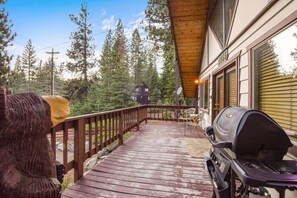 Eine Holterrasse mit Grill, einem Stuhl und einem kleinen Tisch.