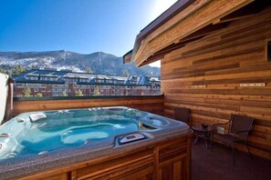 A wooden cabin with a hot tub, outdoor seating, and a view of mountains and buildings. - Downtown Penthouse - Walk to Gondola & Casinos (South Lake Tahoe)