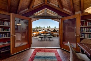 An open room with a view of a patio area, wooden bookshelves, and a red rug. - Downtown Penthouse - Walk to Gondola & Casinos (South Lake Tahoe)
