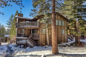 Eine mehrstöckige Holzhütte mit Balkon, umgeben von Schnee und Bäumen.