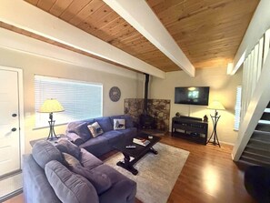 A living room with a sofa, a coffee table, a fireplace, a TV, and a staircase. - Tastefully Updated Incline Village Condo (Incline Village)