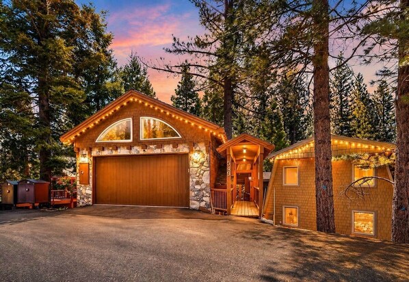Eine Holzhütte mit großer Garage, Steinverkleidungen und einer Veranda mit Lichterketten.