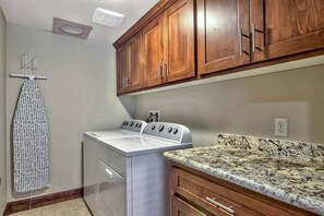 A laundry area with a washing machine, dryer, wooden cabinets, and a granite countertop. - Ideally Located Condo - 6-min Walk to Casinos (South Lake Tahoe)