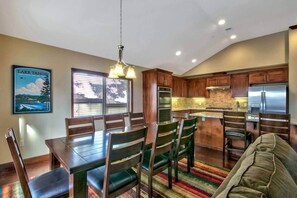 A modern kitchen with wooden cabinets, stainless steel appliances, and a dining area with a table and chairs. - Ideally Located Condo - 6-min Walk to Casinos (South Lake Tahoe)